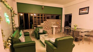 Una sala de estar moderna con sofás verdes, una mesa de centro y un comedor con sillas y una mesa.