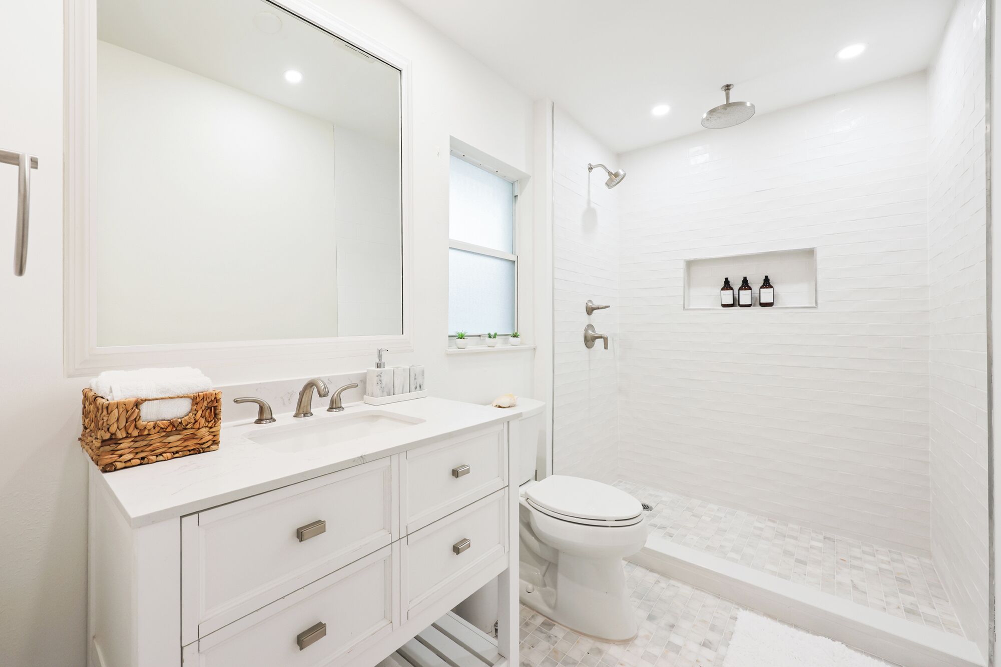 Une salle de bain moderne avec un meuble-lavabo blanc, un grand miroir, des toilettes et un espace douche.