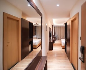 A hotel corridor with wooden doors, a bench, and a bed in the background. - INDORE INTERNATIONAL CONVENTION CENTER (Sanwer)