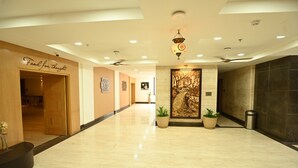 A hotel lobby with a marble floor, a reception desk, a wall with a 'Food for thought' sign, and a large decorative painting. - INDORE INTERNATIONAL CONVENTION CENTER (Sanwer)