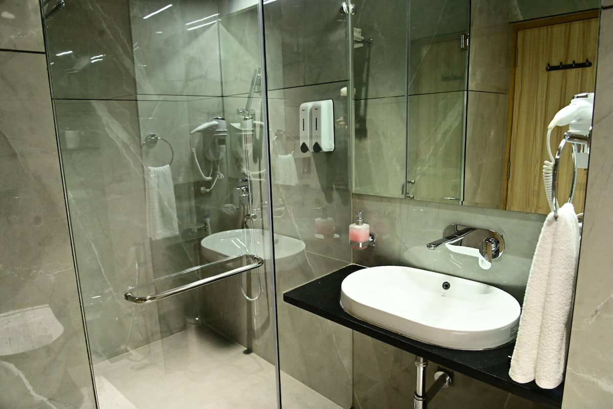 A modern bathroom with a glass-enclosed shower, a white sink, and a mirror.