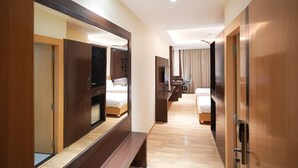 A hotel room with a large bed, a desk, a chair, a TV, and a mirror. - INDORE INTERNATIONAL CONVENTION CENTER (Sanwer)