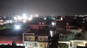 Vista nocturna de una zona residencial con varios edificios, algunos con tejados visibles y otros con ventanas iluminadas.