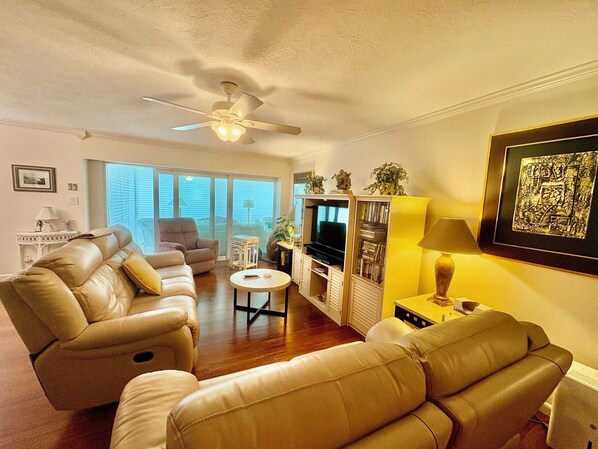 A living room with a sofa, armchair, TV, and bookshelf.