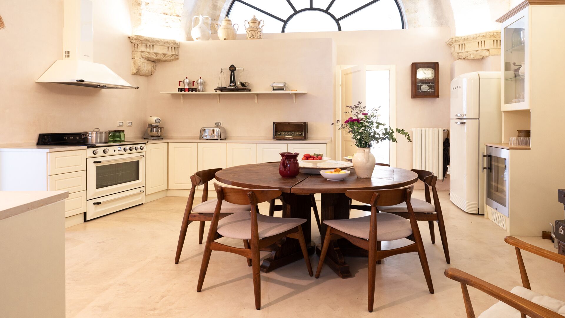 A kitchen with a round wooden table, white cabinets, and a built-in oven.