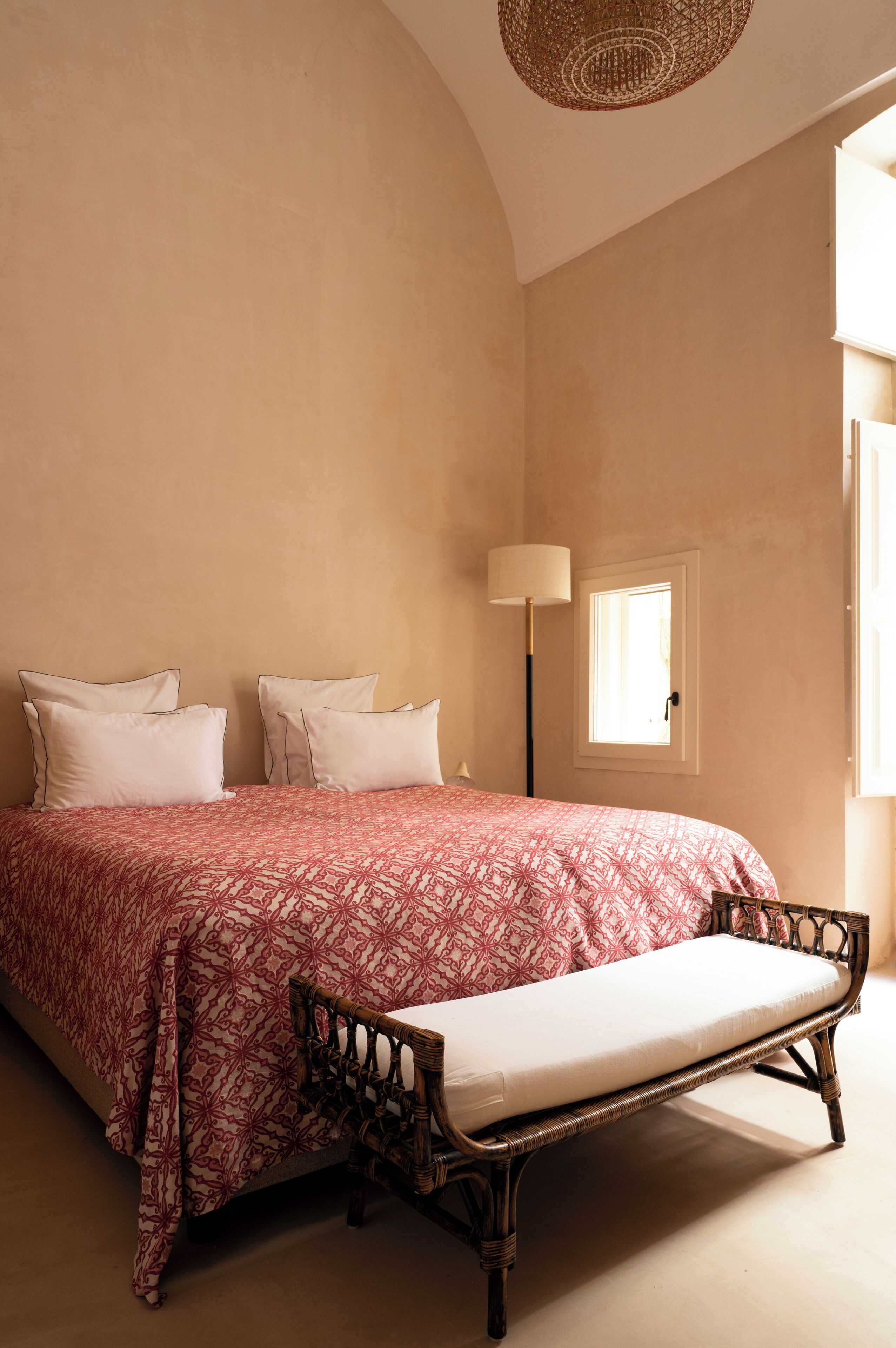 Un dormitorio con una cama grande, una mesita de noche, una lámpara y una ventana.