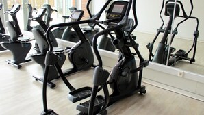 Una palestra con diverse macchine per esercizi, un grande specchio e un pavimento in legno.