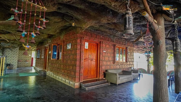 Un interior que recuerda a una cueva, con una puerta de madera, una campana colgante y un banco.