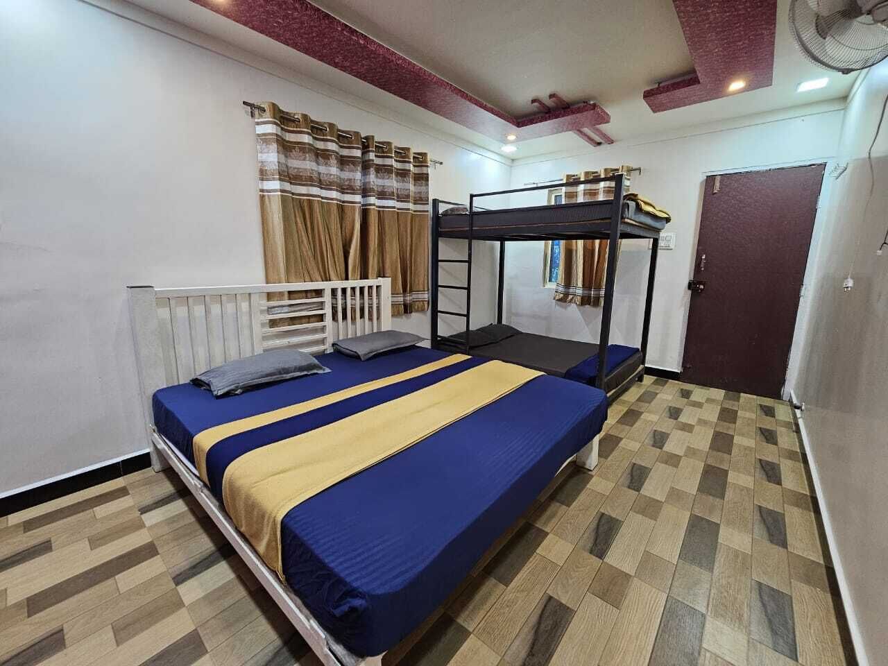 A room with a bunk bed, a single bed, a window with curtains, a door, and a fan on the ceiling.