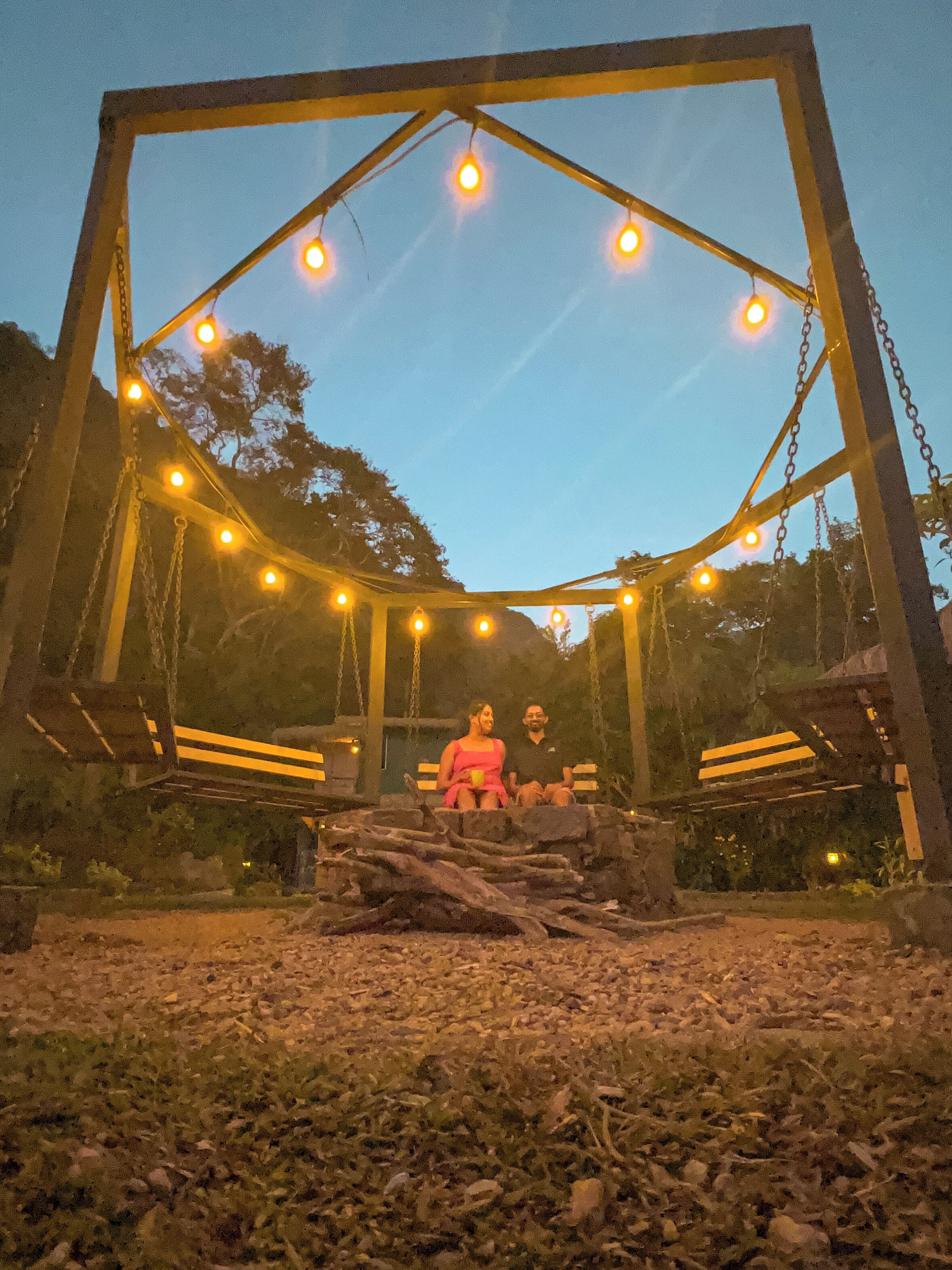 A swing set with lights, surrounded by rocks and trees.