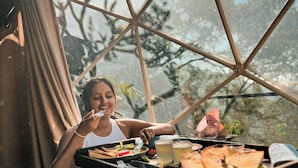 A dining area with a glass table and metal frame, surrounded by curtains and a view of trees. - Glamping by Offtrek (Medamahanuwara)
