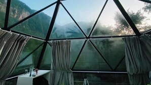 A geodesic dome room with a view of mountains, a hanging light fixture, and green bean bag chairs. - Glamping by Offtrek (Medamahanuwara)