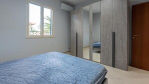 Een slaapkamer met een bed, een raam en een kledingkast.