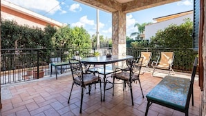 Een terras met een ronde tafel en stoelen, omgeven door een stenen boog.