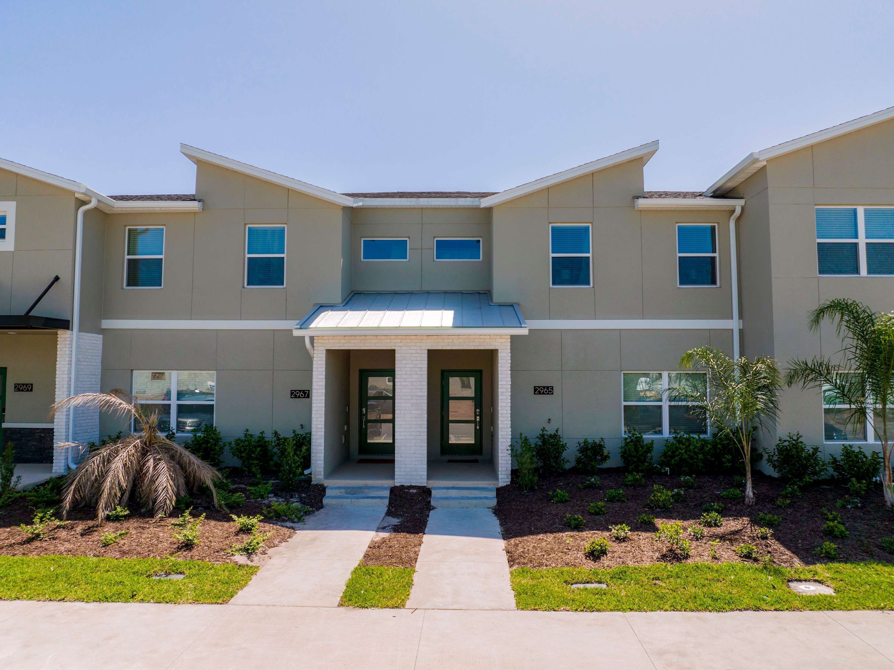A modern two-story building with a symmetrical facade, a central entrance with a door, and a small porch area.