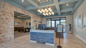 A reception area with a stone wall, a blue reception desk, and a sign instructing to check-in at the front desk. - Disney Getaway Prime Location Themed Rooms (Kissimmee)