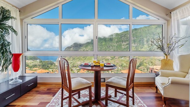 A dining area with a large window overlooking a mountainous landscape. - Landure Penthouse by Homie (São Vicente)