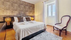A hotel room with a bed, a chair, a nightstand, and a lamp.