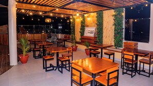 A restaurant with wooden tables and chairs, potted plants, and a sign indicating a cashless payment option. - Sechura Hotel Casa Blanca Piscina Garaje (Sechura)