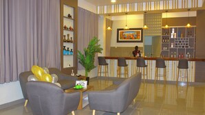 A modern lobby with grey sofas, a bar area, and a large potted plant. - Sechura Hotel Casa Blanca Piscina Garaje (Sechura)