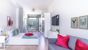 A modern, well-lit living room with a sofa, a bed, and a dining area. - Pirandello 4 - Studio Apartment, Sleeps 4 (Milano)