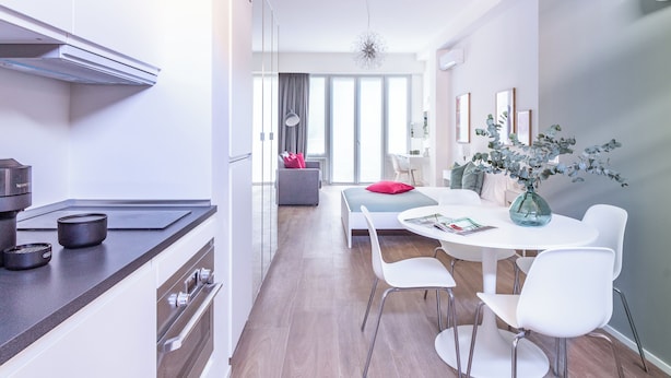 A modern kitchen with a built-in oven and a dining area with a white table and chairs. - Pirandello 4 - Studio Apartment, Sleeps 4 (Milano)