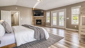Une chambre à coucher avec un lit, une cheminée, une télévision et un ventilateur de plafond.