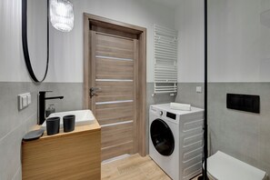 Bathroom features a clean design with a sink, washing machine, and towel rack.