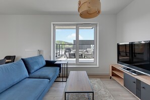 Relax in this stylish living room with a large window, sofa, coffee table, and flat-screen TV.