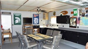 Ein Zimmer mit Esstisch, Stühlen, einem Fernseher und Erinnerungsstücken der Michigan State University.