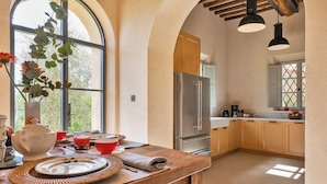 A kitchen with a wooden countertop, stainless steel appliances, and a view through an arched window.