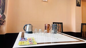 Une table avec une bouilloire, deux carafes et quatre verres, une brochure et un luminaire fixé au mur.