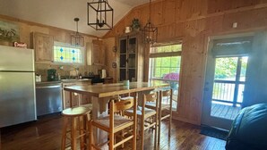 A rustic kitchen with wooden floors, a central island with stools, and hanging light fixtures.
