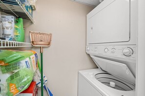 A laundry area with a washing machine, a mop, and cleaning supplies.