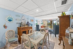 A room with a dining table, chairs, a sofa, and a cabinet.