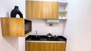 Een keuken met houten kastjes, een zwarte kookplaat en een zwarte vaas op het aanrecht.