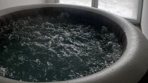 Un bain à remous avec vue sur un paysage montagneux, visible à travers une grande fenêtre.