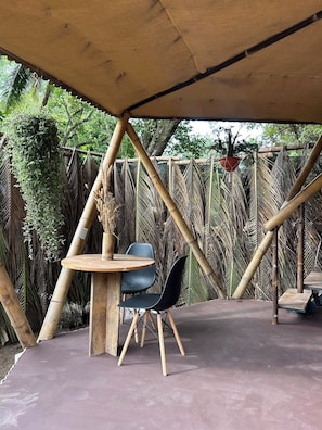An outdoor seating area with a round table and two chairs, surrounded by bamboo structures and greenery. - Bambuk Bio Chalet Uvita beach front (Uvita)