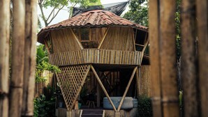 A bamboo house with a thatched roof, a balcony, and a small staircase leading to the entrance. - Bambuk Bio Chalet Uvita beach front (Uvita)
