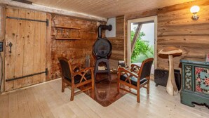 A rustic wooden room with a fireplace, wooden chairs, a small table, and a decorative vase. - Chalet in Rossiniere With Sauna and Mountain Views (Chateau-d'Oex)