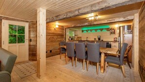 A wooden interior with a dining area, kitchen, and a door leading outside. - Chalet in Rossiniere With Sauna and Mountain Views (Chateau-d'Oex)