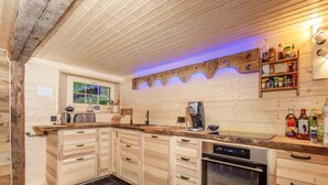 A modern kitchen with wooden cabinets, a built-in oven, and a coffee machine. - Chalet in Rossiniere With Sauna and Mountain Views (Chateau-d'Oex)