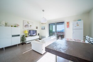 Relax in this stylish living space with a sofa, flat-screen TV, dining area, and kitchen with a view of the outdoors.