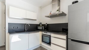 A modern kitchen with white cabinets, a stainless steel refrigerator, a microwave, and a built-in oven.