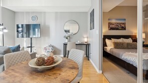 A modern living room with a round dining table, a sofa, a TV, and a bed with a headboard. - Beautiful and Stylish 1 BR Condo in DT Toronto (Toronto)