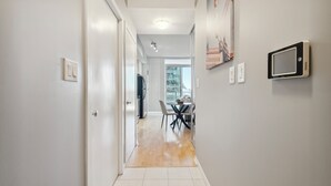 A hallway with a dining area at the end, featuring a table and chairs, a ceiling light, and a wall-mounted device. - Beautiful and Stylish 1 BR Condo in DT Toronto (Toronto)
