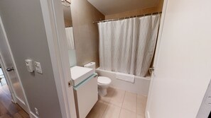 Une salle de bain équipée de toilettes, d’une baignoire et d’un rideau de douche.