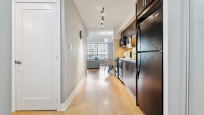A modern kitchen with a stainless steel refrigerator, wooden cabinets, and a light-colored floor. - Charming 1-BR Condo in DR Toronto (Toronto)
