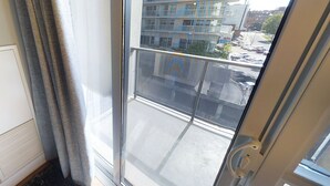 A view from a window with a metal railing, looking out at a building with multiple floors and a parking lot below. - Charming 3-BR Condo in DR Toronto (Toronto)