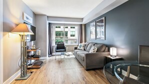 Ein modernes Wohnzimmer mit einer Couch, einem Glastisch, einer Stehlampe und einem Fernseher.